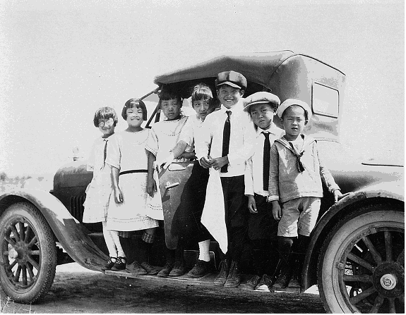Children posing on a car at the Kishi farm, ca 1922.
