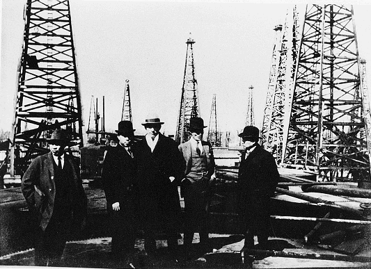 A group of men, including Yamamoto, in front of the oil derricks at Orangefield