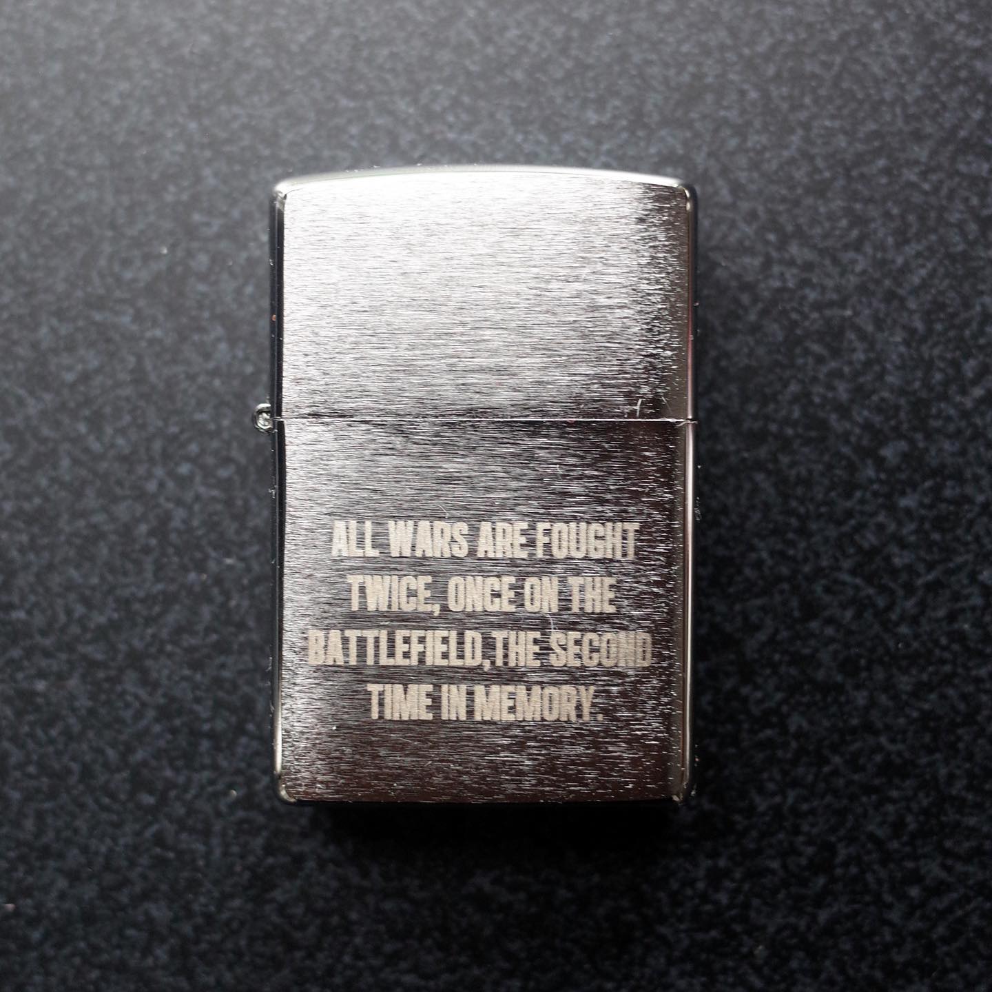 Zippo style lighter with the engraving "ALL WARS ARE FOUGHT TWICE, ONCE ON THE BATTLEFIELD, THE SECOND TIME IN MEMORY."