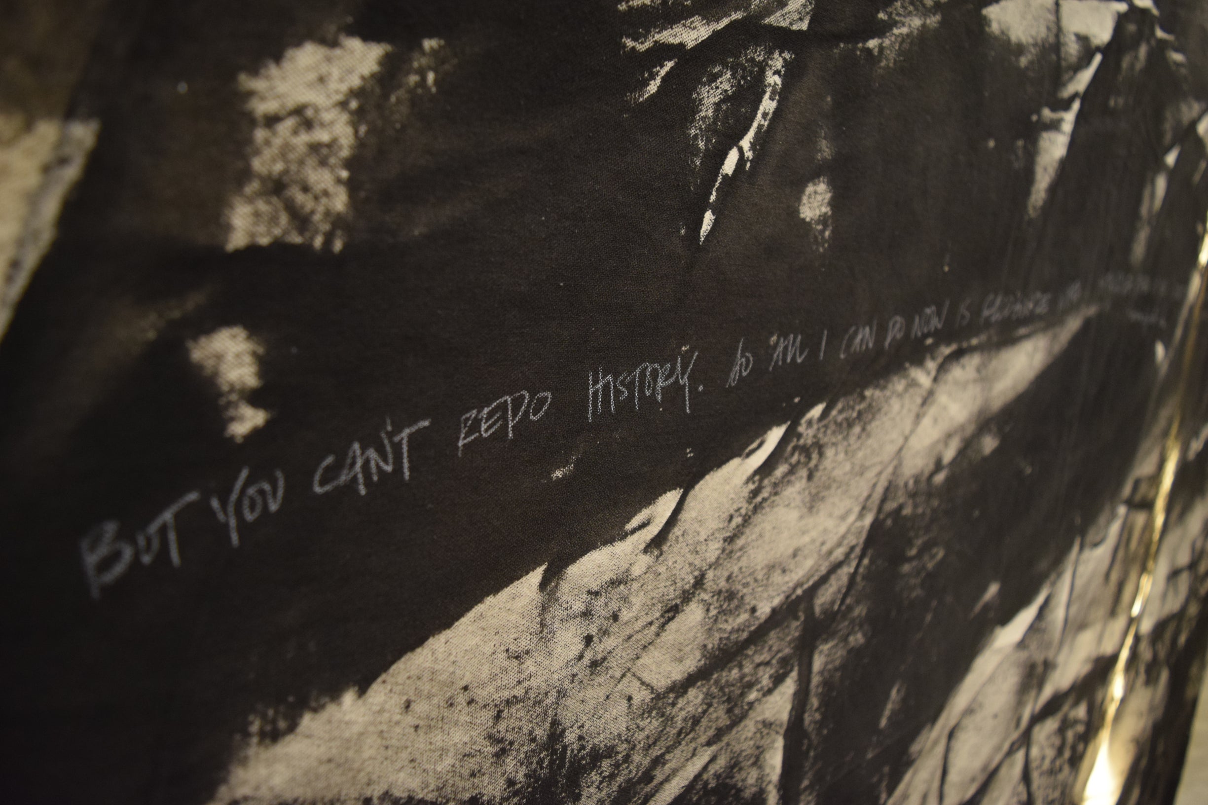 "But you can't redo history..." written in white chalk over black paint on canvas