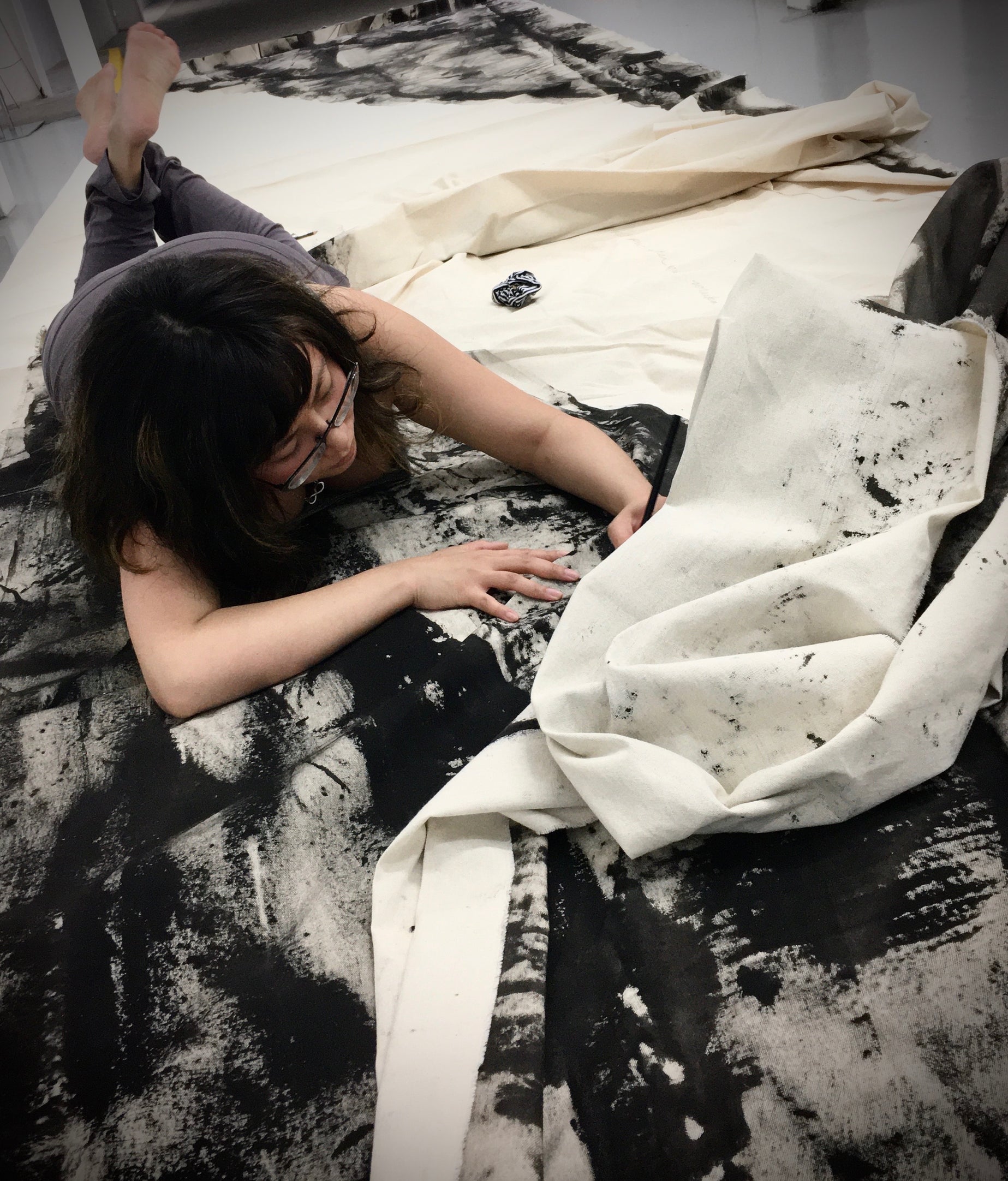 Rachel Gonzales lays on top of the Portal of Healing canvas drawing on it