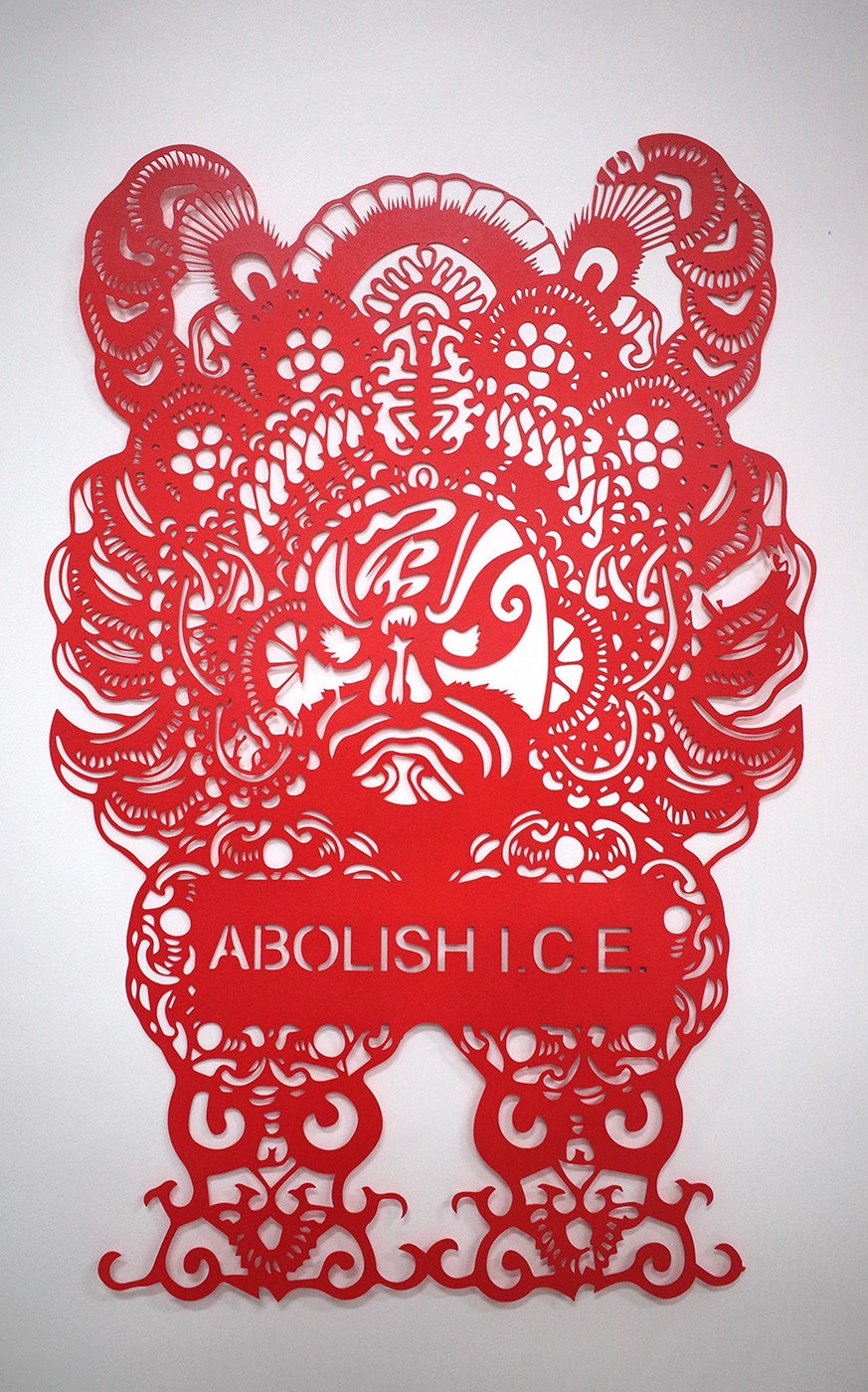 Red paper cutting that reads "ABOLISH ICE"