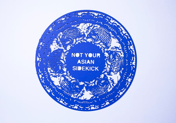 Blue paper cutting that reads "NOT YOUR ASIAN SIDEKICK"