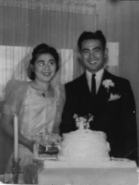 Mas and Lily Yamasaki at their wedding standing behind their wedding cake