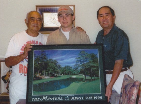 Three generations of Yamasakis holding a Masters poster