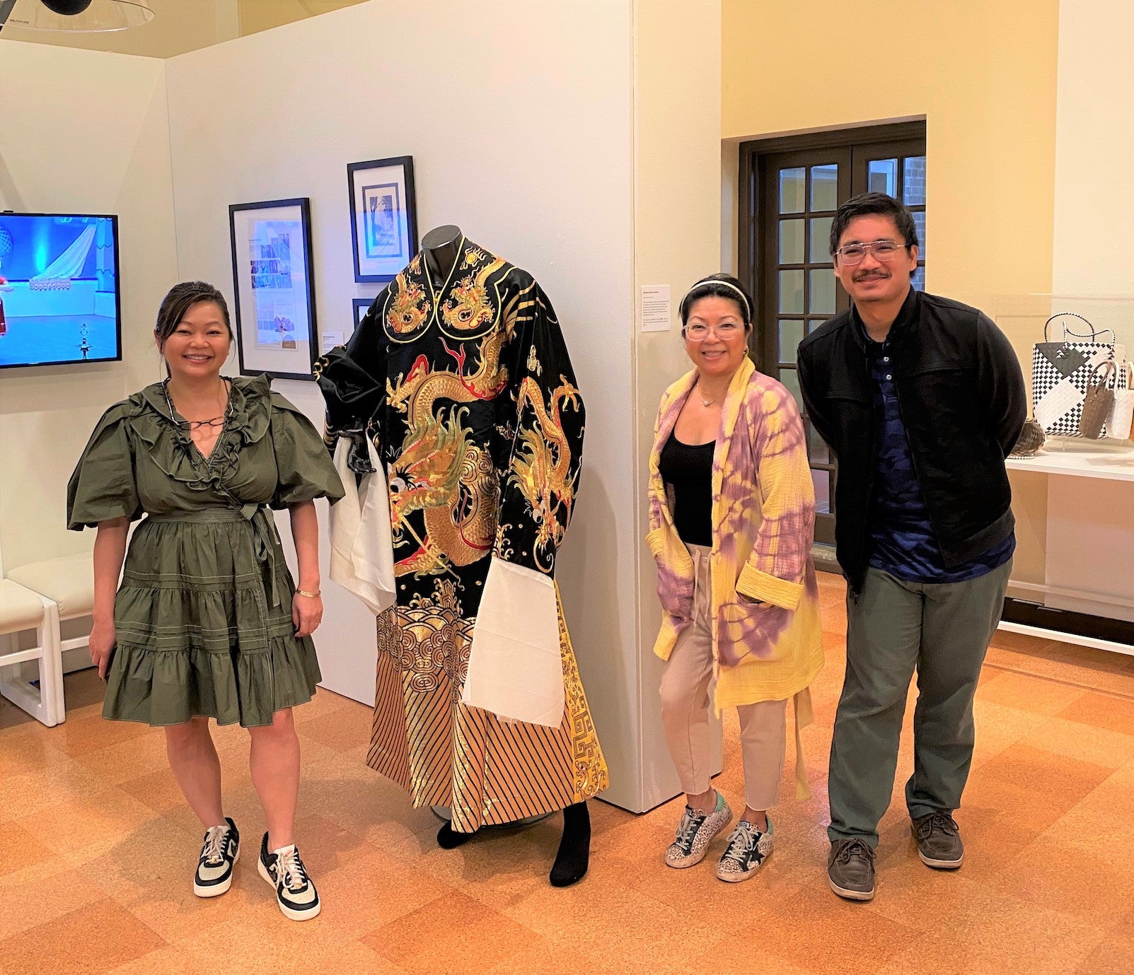 Two women and a man pose with a manequin wearing an elaborate kimono