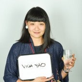 Vida Yao holding a small whiteboard with her name and a glass of water